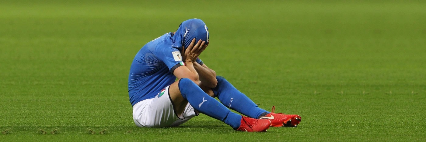 Italian player sitting on the pitch with head in hands after a defeat